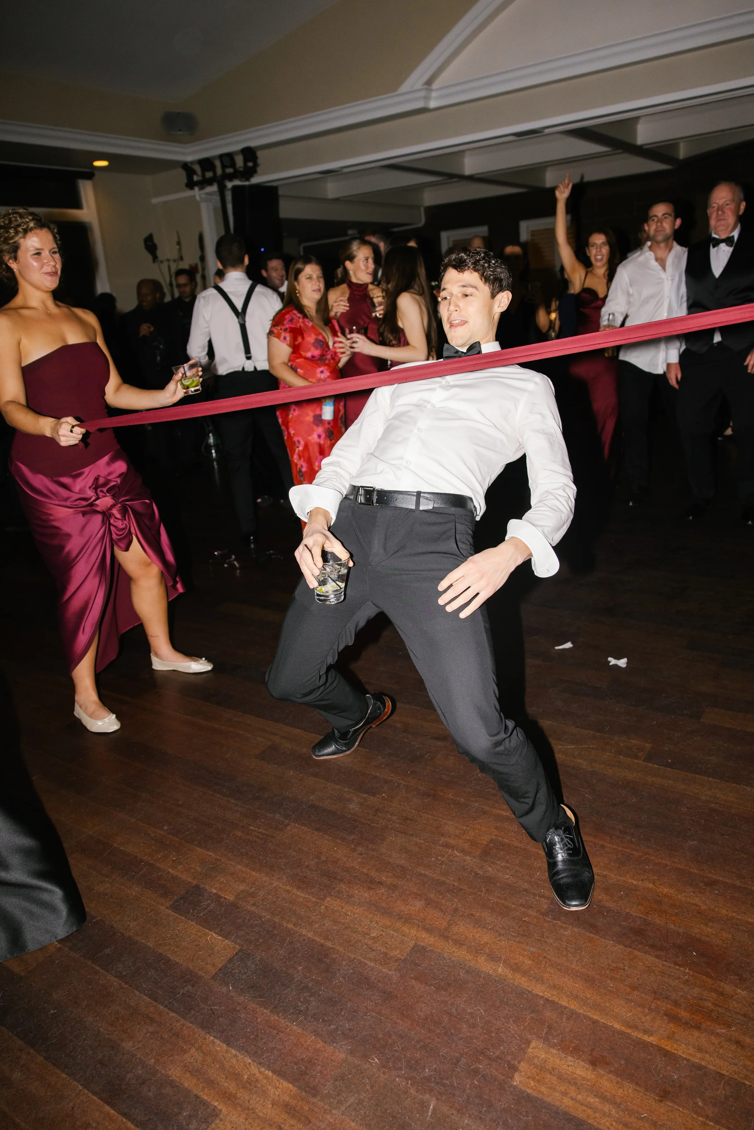 Wedding guest doing the limbo on the dance floor at a lively reception with live band entertainment by Soul City Band in Newport RI
