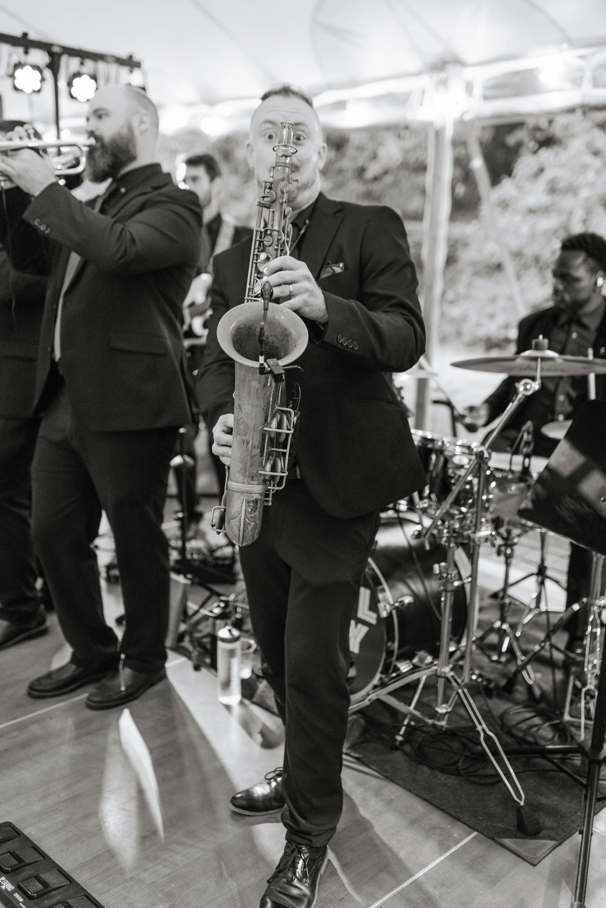 Soul City Band saxophonist performing live at a tented wedding reception in Newport, RI, with trumpet player and drummer visible in background