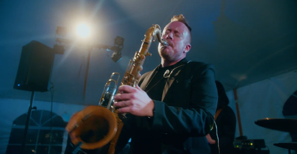 Soul City Band saxophonist Tucker Antell performing live under blue stage lighting at a wedding reception in Newport RI or Boston MA