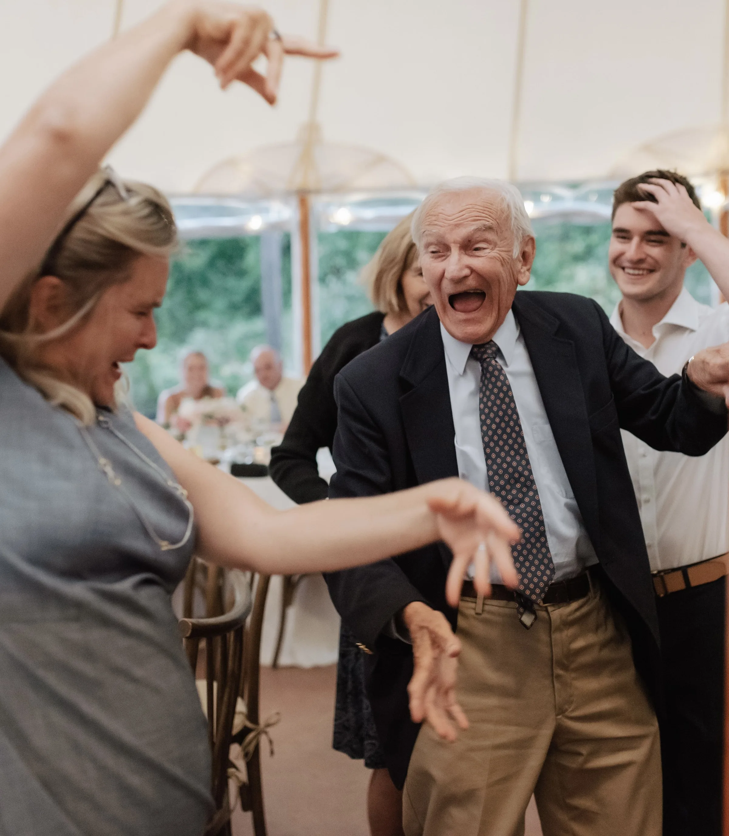 Joyful elderly guest dancing with energy at a tented wedding reception, captured at a New England wedding celebration featuring live band entertainment by Soul City Band in Newport RI