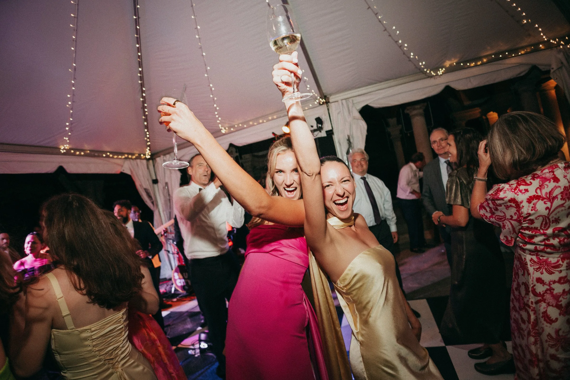Guests dancing and celebrating with champagne at a tented wedding reception with live band entertainment by Soul City Band in Newport RI