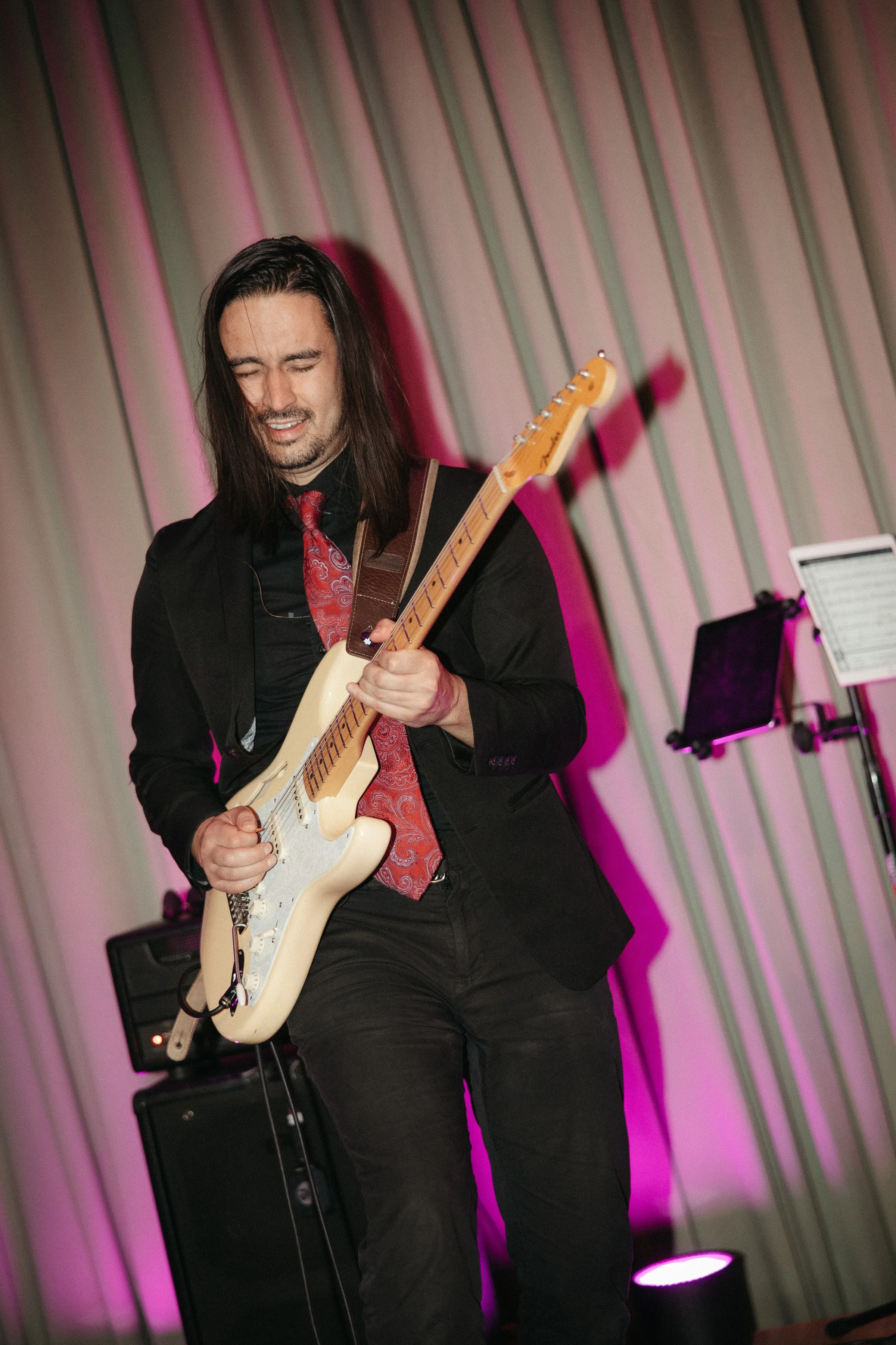 Soul City Band guitarist performing live at a wedding event in Newport RI, playing a Fender Stratocaster electric guitar in a black suit and red paisley tie
