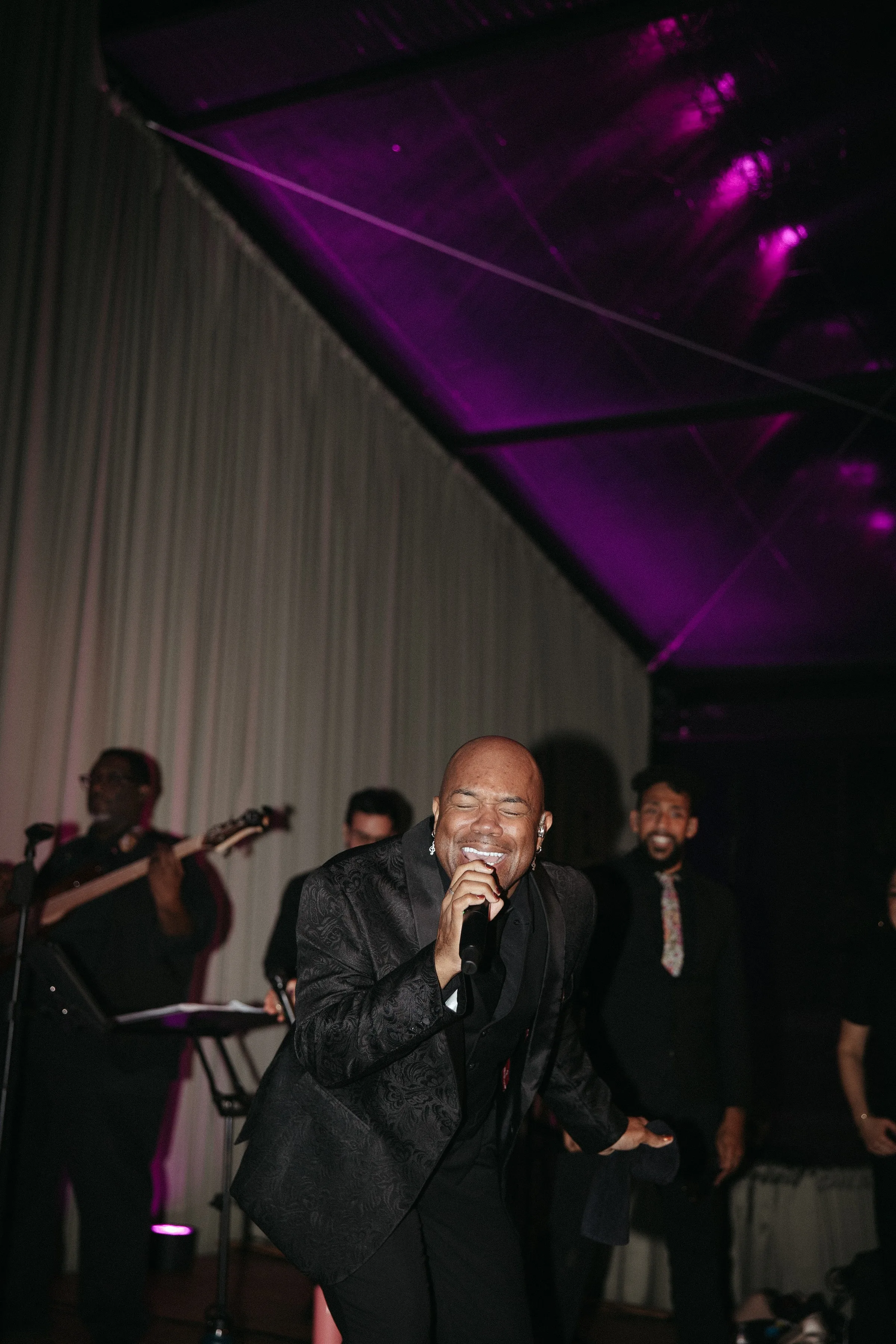 Soul City Band lead singer performing with microphone at a live wedding reception under purple stage lighting in Newport RI