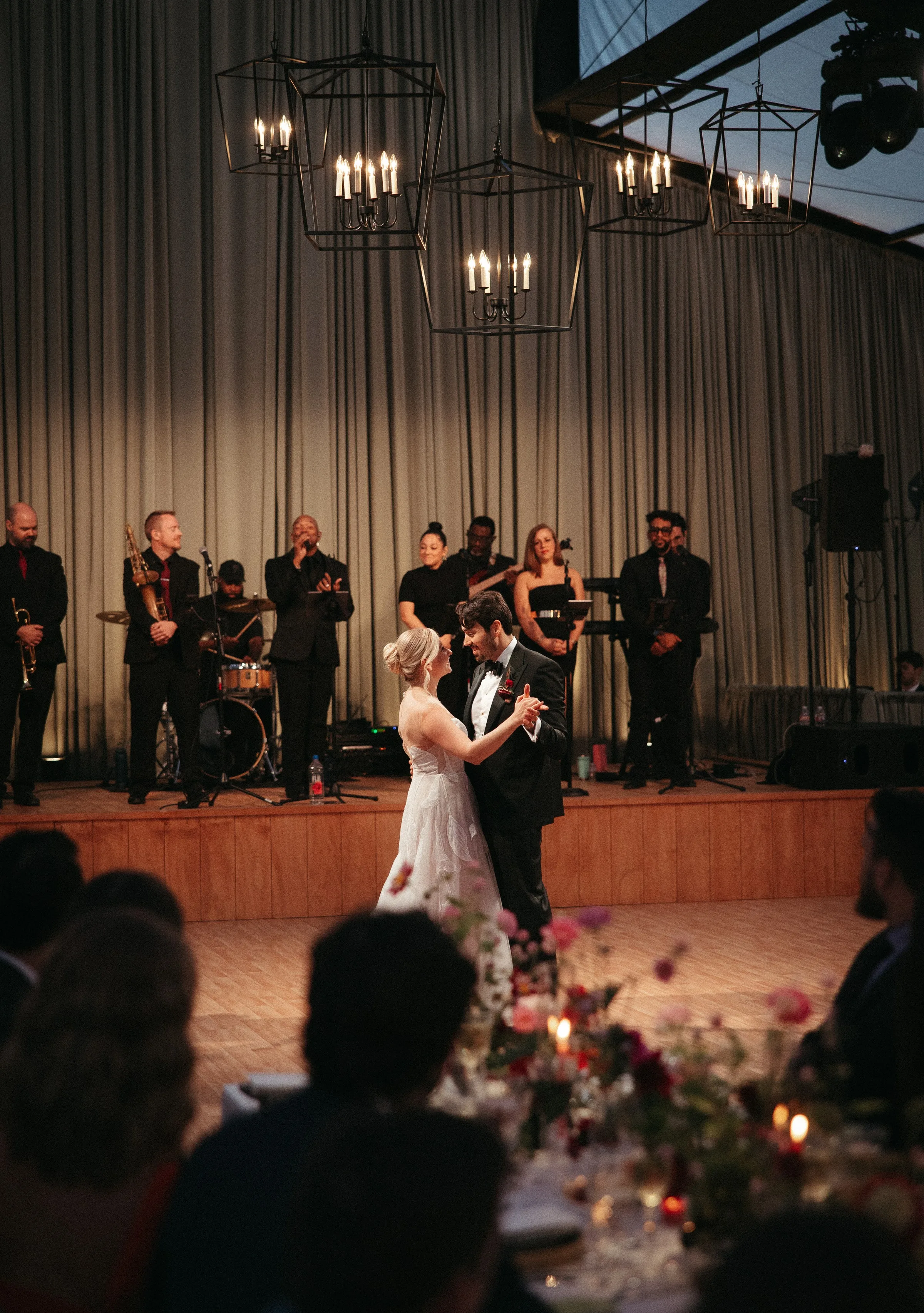 Bride and groom share their first dance in front of Soul City Band performing live at an elegant wedding reception with geometric chandeliers