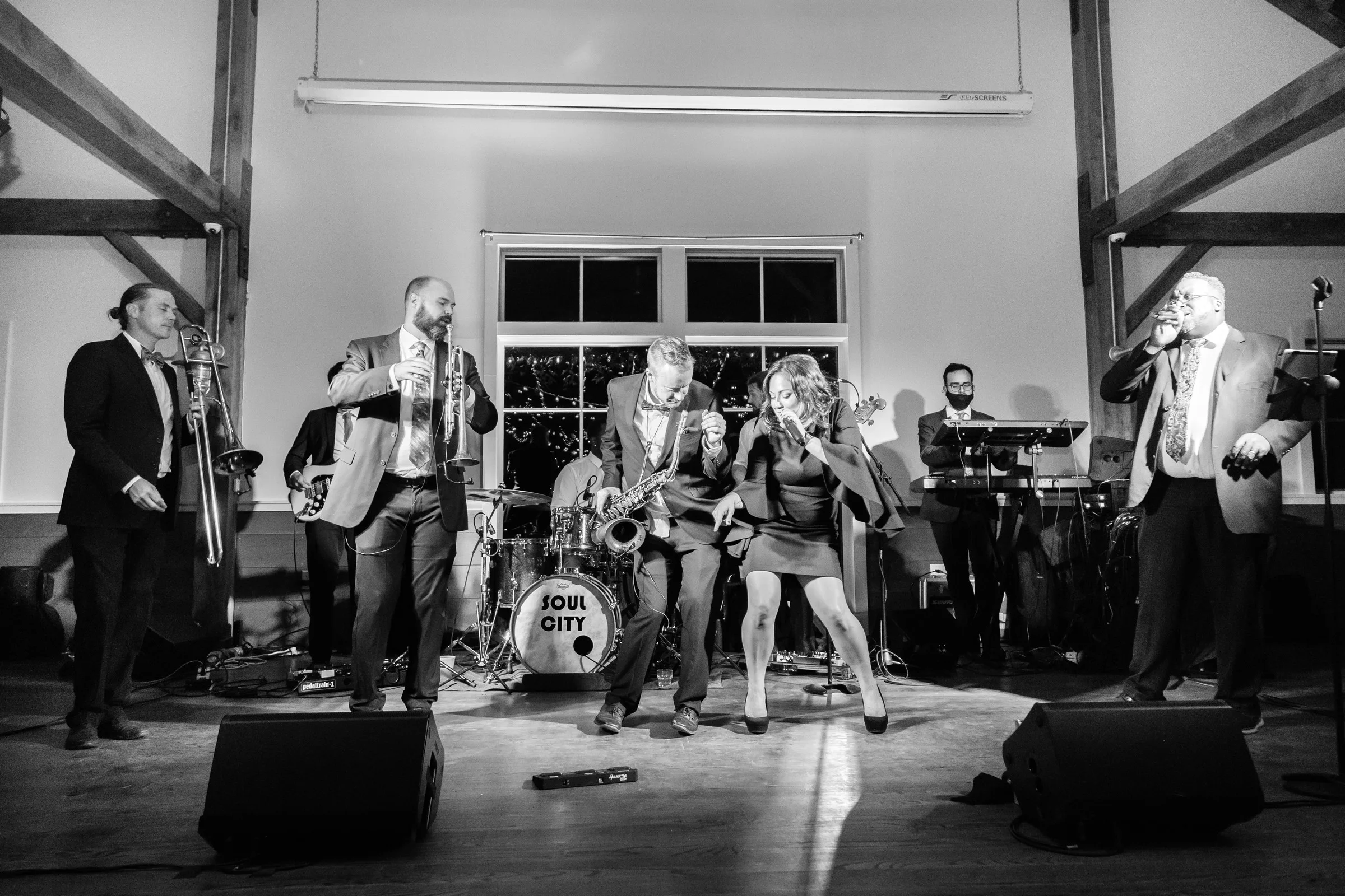Soul City Band performing live with brass horns, saxophone, and vocals at a wedding reception in Newport RI, with the band name visible on the bass drum
