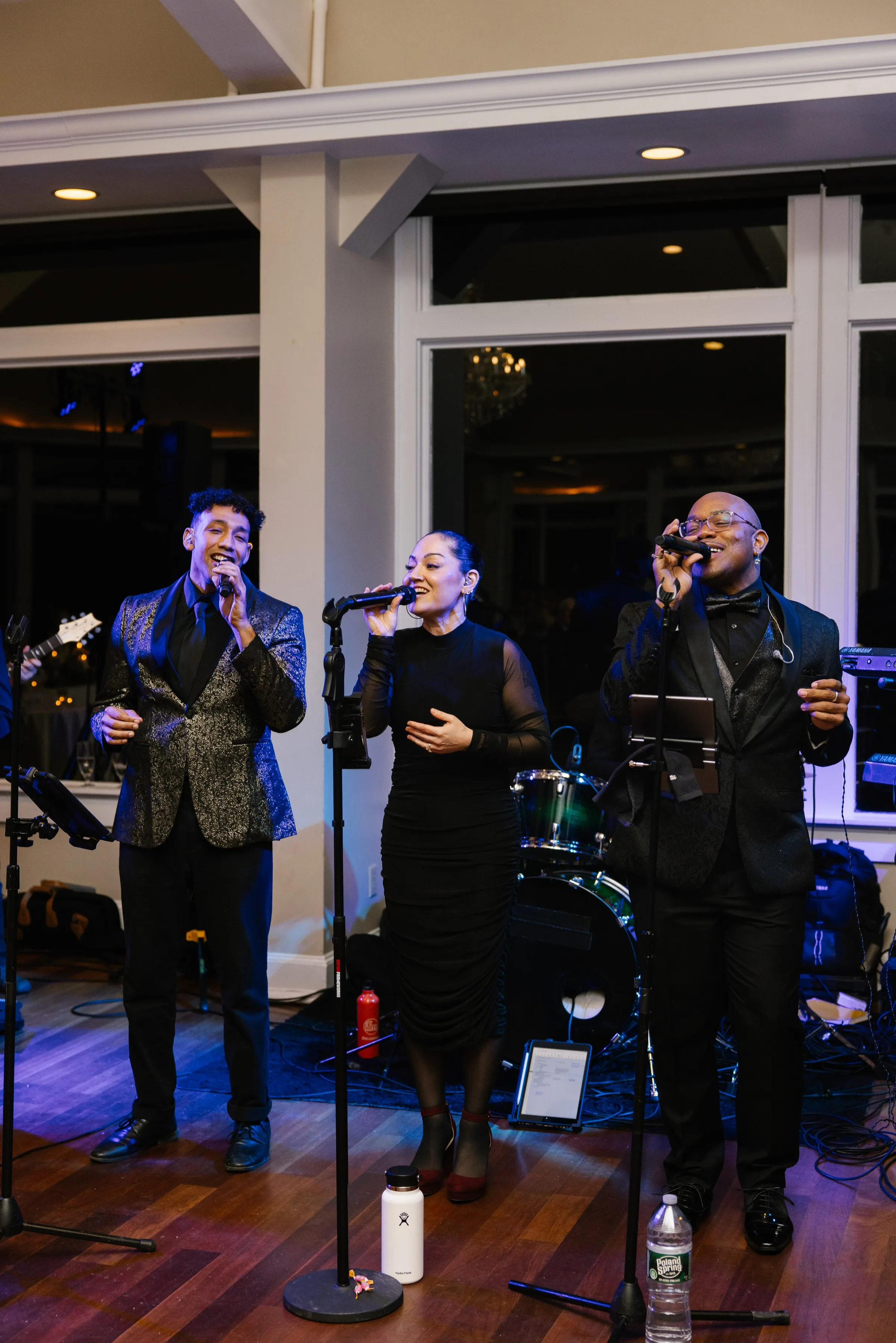Soul City Band vocalists performing live at an elegant wedding reception in Newport, RI, with three singers in formal attire singing into microphones on a hardwood dance floor