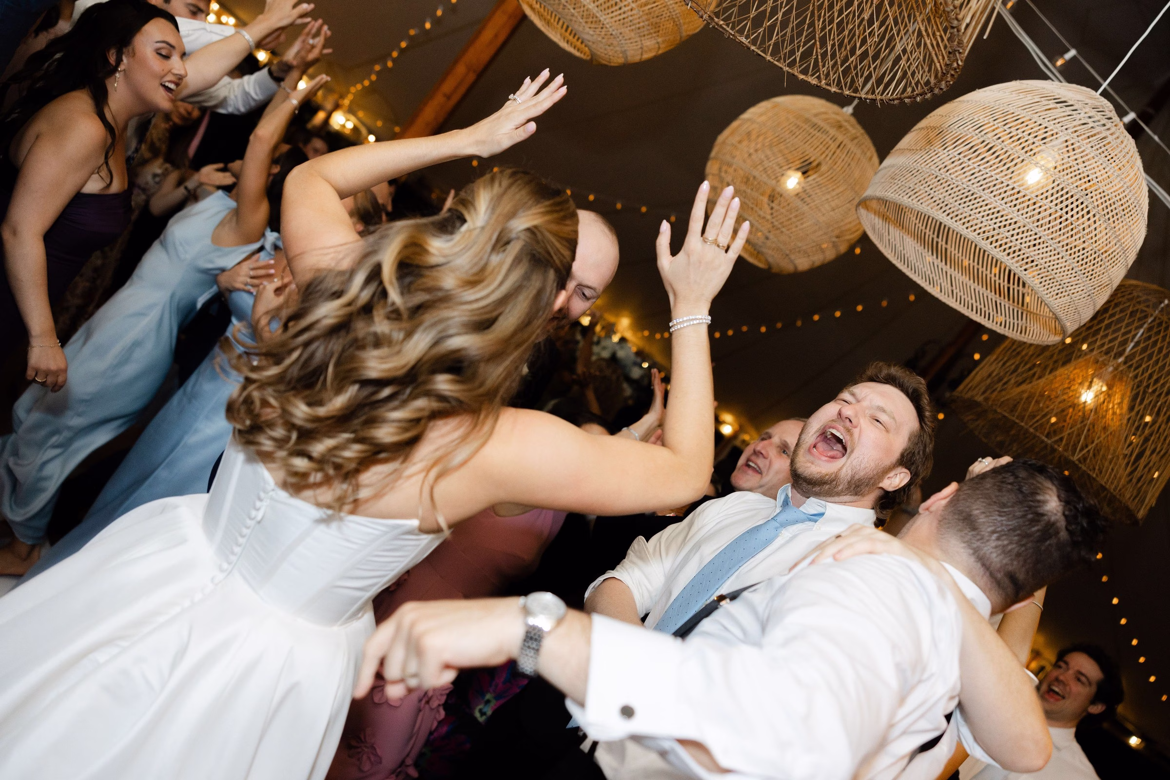 Bride and groom dancing energetically with wedding guests at a lively reception party, with wicker pendant lights overhead, performed by Soul City Band in Newport RI